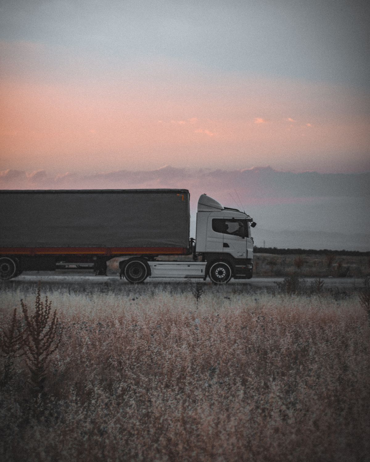 Cargo truck moving materials along a highway at dusk