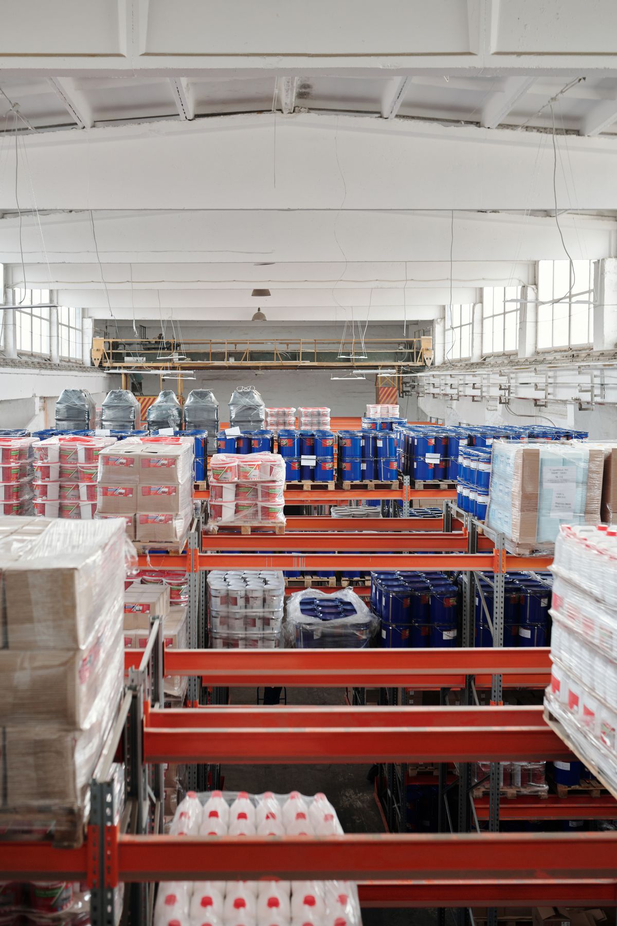 Fully stocked warehouse racking with palletized drums and boxed materials